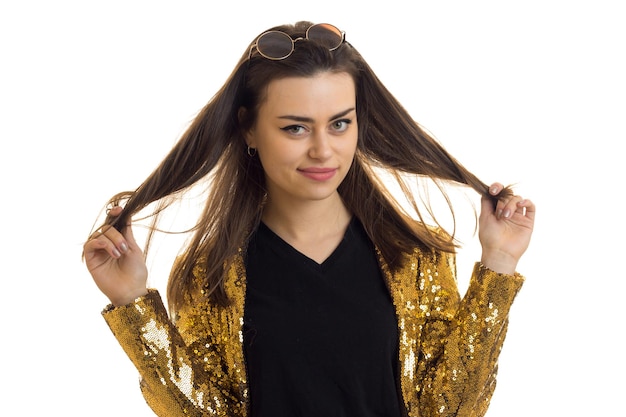 Young beautiful brunette in a gold jacket keeps hands hair and smiling isolated on white background