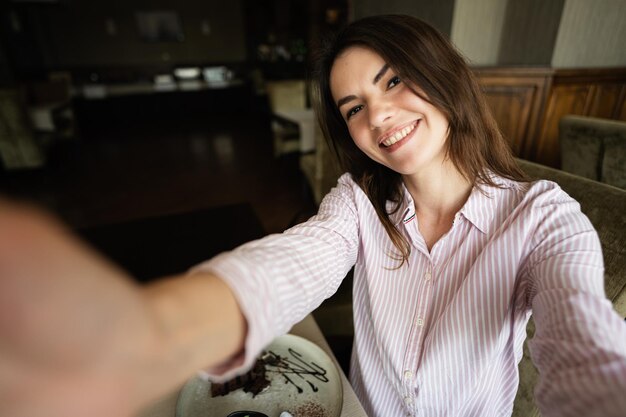 Photo young beautiful brunette restaurant indoors hold camera and making selfie