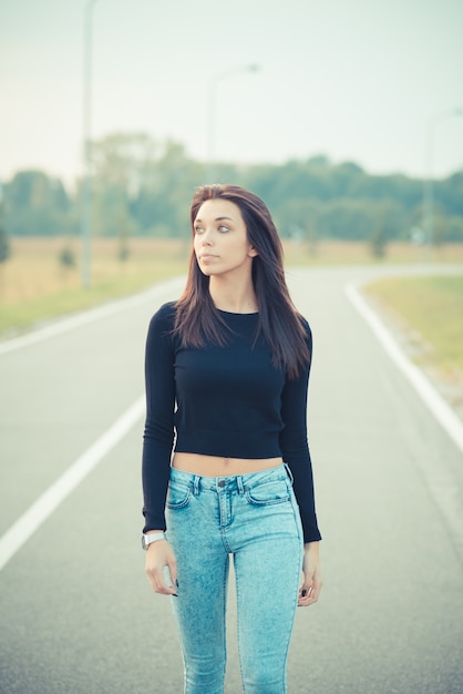 道路上に若い美しいブルネットストレート髪の女性