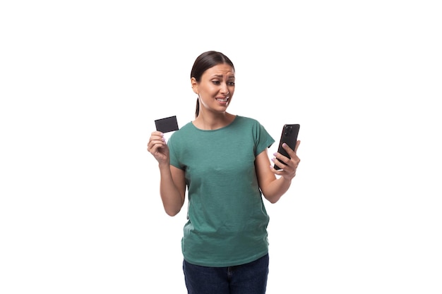 Young beautiful brunette woman dressed in a green tshirt holding a credit card with mockup