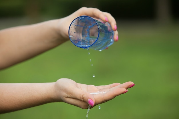 Foto giovane bella donna bruna che beve acqua dalla bottiglia in un parco a