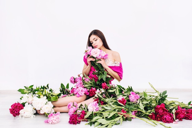 Young beautiful brunette woman model with beautiful makeup and long hair in pink colors  peonies