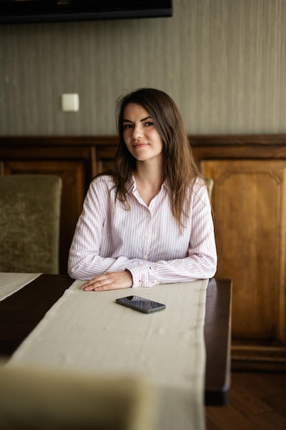 La giovane bella donna castana si siede nel ristorante del caffè della caffetteria all'interno