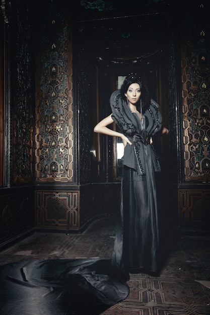 Фото Молодая красивая брюнетка женщина, стоящая в комнате дворца