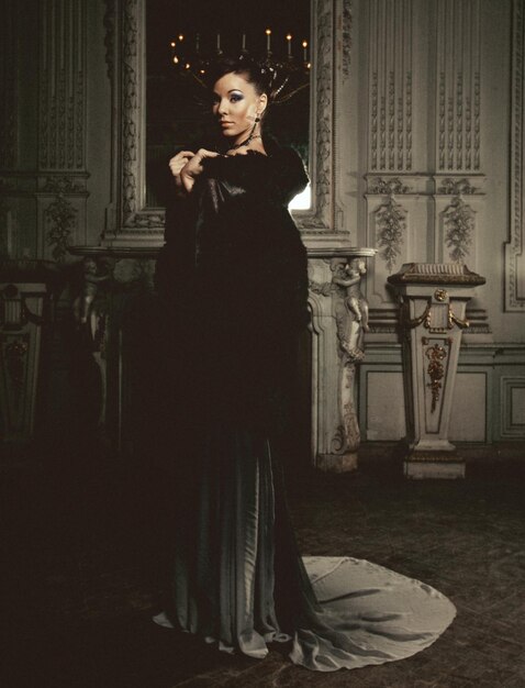 Young beautiful brunette woman standing in the palace room