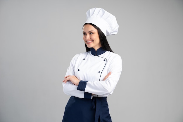 Giovane bella donna castana che indossa l'uniforme che guarda lontano mentre si sente positiva e felice. signora in piedi con un sorriso sicuro