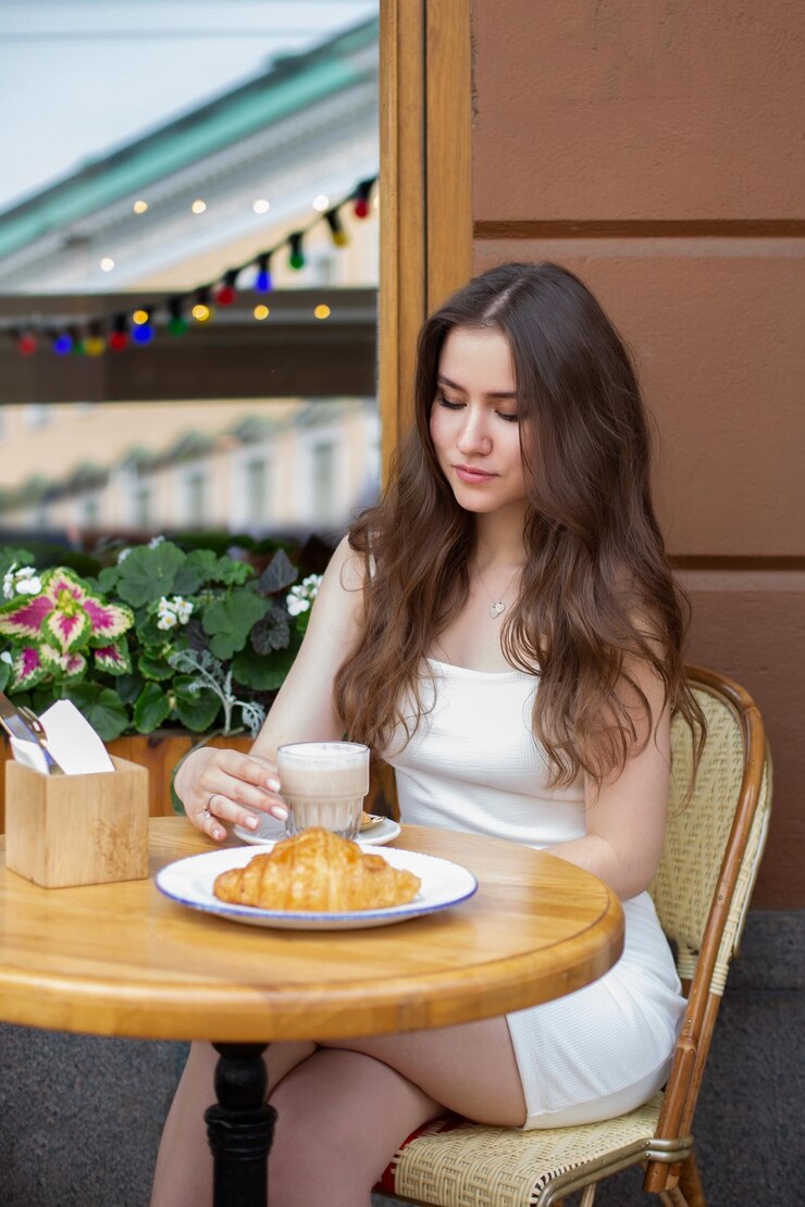 Photo young beautiful brunette woman in white dress drinking coffee in summer cafe