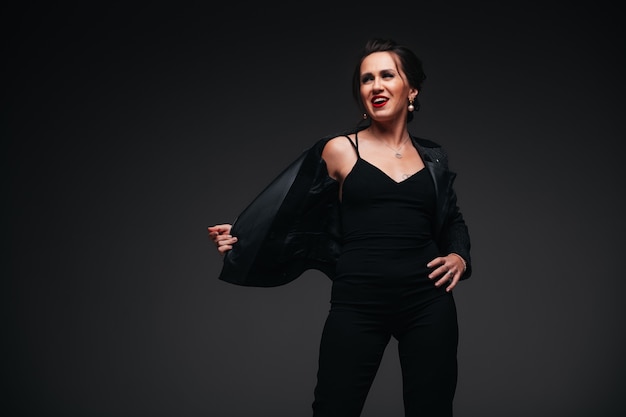 Young beautiful brunette woman with red lips on black background