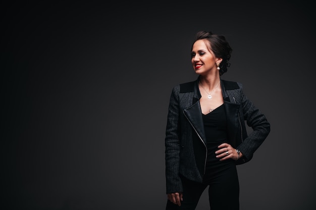 Young beautiful brunette woman with red lips on black background