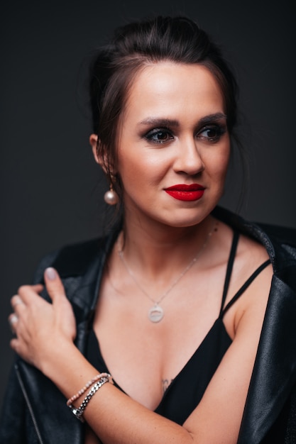 Young beautiful brunette woman with red lips on black background