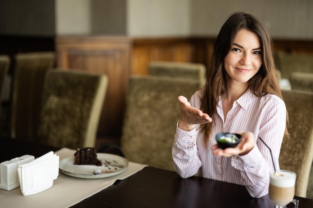 Young beautiful brunette womanrestaurant indoors and eat chocolate brownie dessert cake show plate