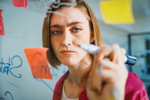 Young beautiful business leader writing marketing idea on board Immaculate