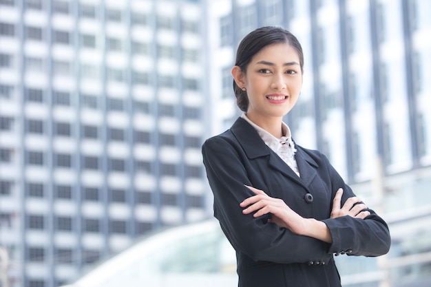 Foto la giovane bella donna di affari che sta nella città che guarda e aspetta per lavoro.