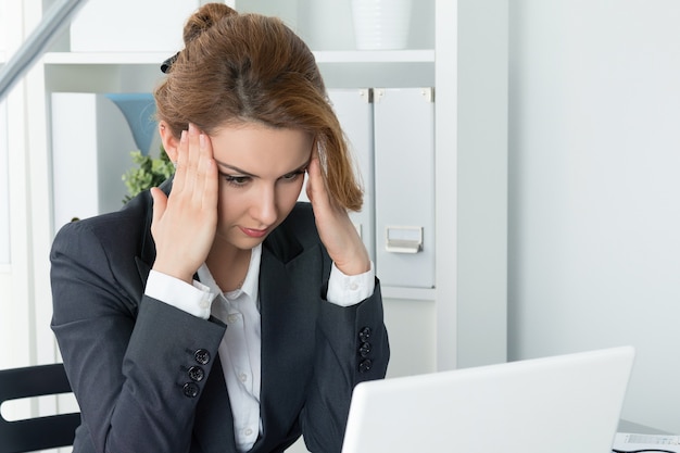 Young beautiful business woman trying to concentrate looking at laptop monitor