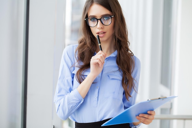 Young beautiful business woman with clipboard in the office.