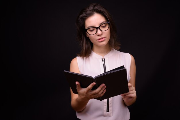  young beautiful businesswoman against black wall