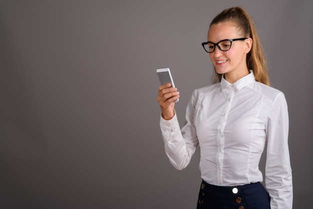 Young beautiful businesswoman against gray background