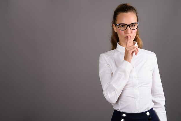 Young beautiful businesswoman against gray background