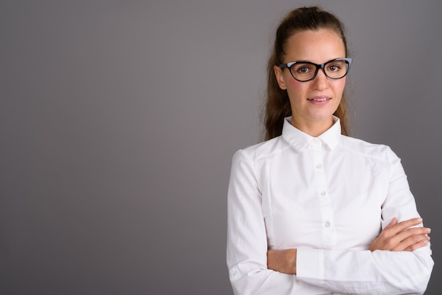 Young beautiful businesswoman against gray background