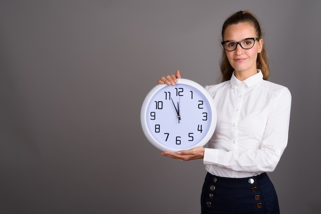 Young beautiful businesswoman against gray background