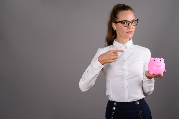 Young beautiful businesswoman against gray background