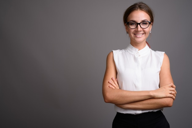 Young beautiful businesswoman against gray wall