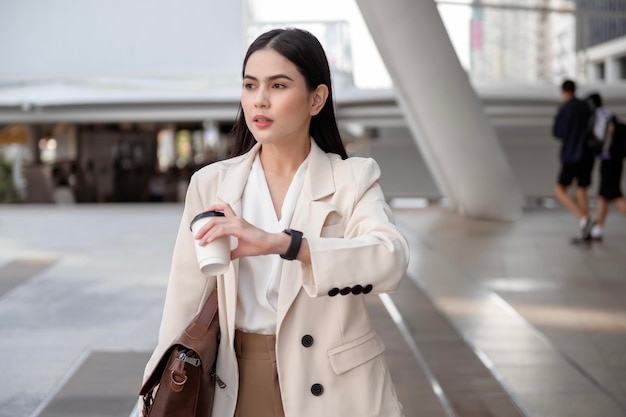 Young beautiful businesswoman in a hurry checking time and running in modern city