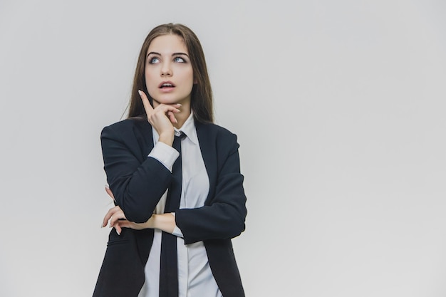 Young beautiful businesswoman is thinking with her hand on chin Curious businesswoman came up with an idea