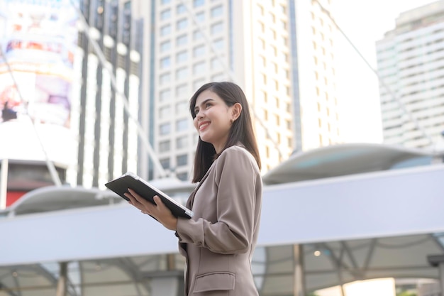 Una giovane bella donna d'affari sta usando il tablet nella città moderna