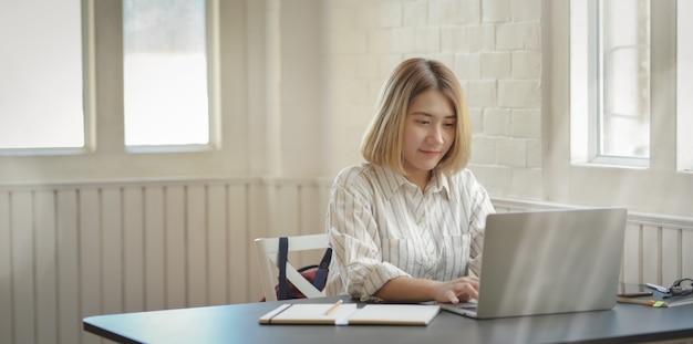 랩톱 컴퓨터에 입력하는 젊은 아름다운 사업가