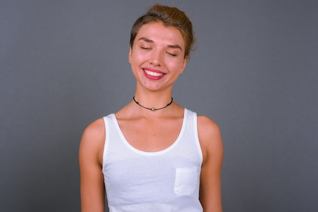 Young beautiful businesswoman with blond hair on gray