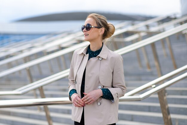 Young beautiful businesswoman with sunglasses, phone, laptop, cup of coffee in the city streets.