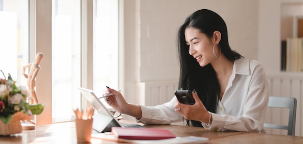 快適なオフィスでデジタルタブレットで彼女のプロジェクトに取り組んでいる若い美しい女性実業家