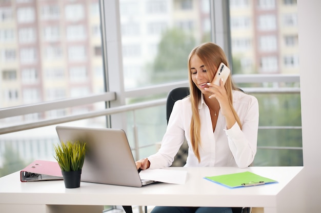 Young beautiful businesswoman working on laptop in bright modern office