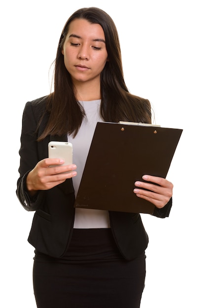 Young beautiful Caucasian businesswoman using mobile phone while holding clipboard