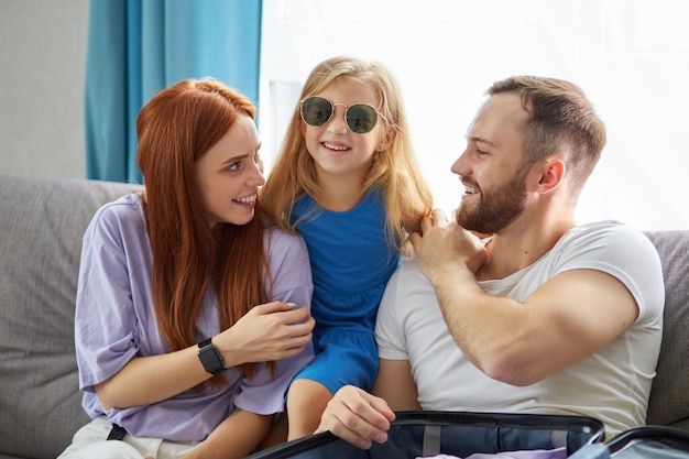 Young and beautiful caucasian family with child packing suitcase