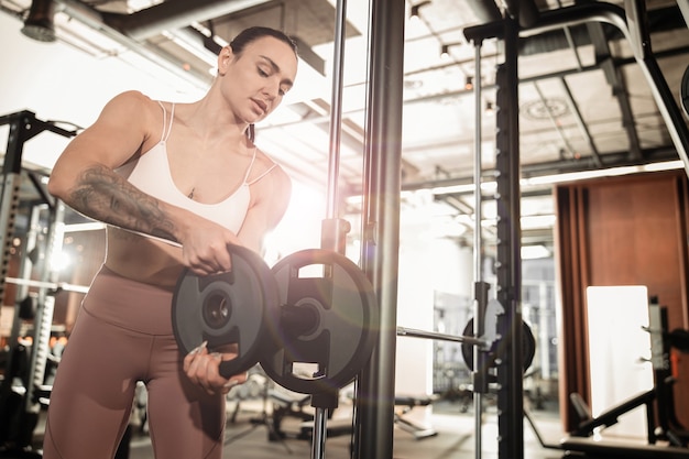 La giovane bella donna caucasica in forma forte sta facendo esercizi in palestra