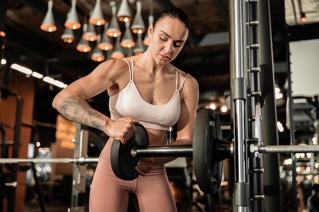 La giovane bella donna caucasica in forma forte sta facendo esercizi in palestra