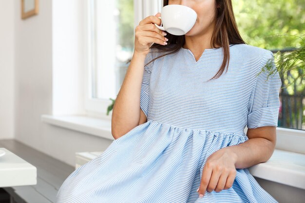 Young beautiful Caucasian lady enjoy drinking and having dessert in modern coffee shop at noon