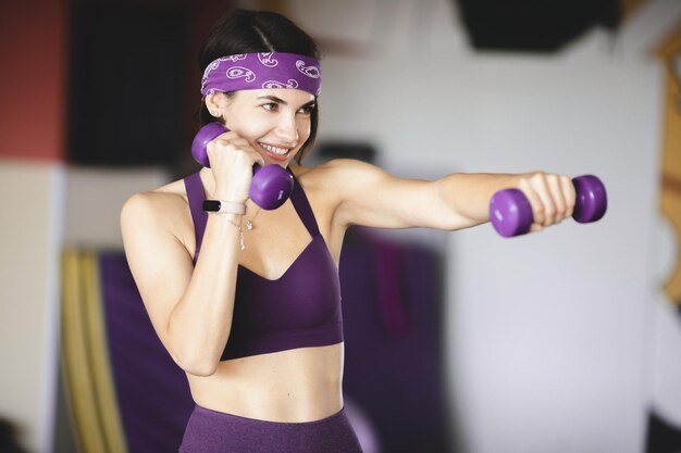 Giovane bella donna caucasica che fa esercizi con il manubrio in palestra