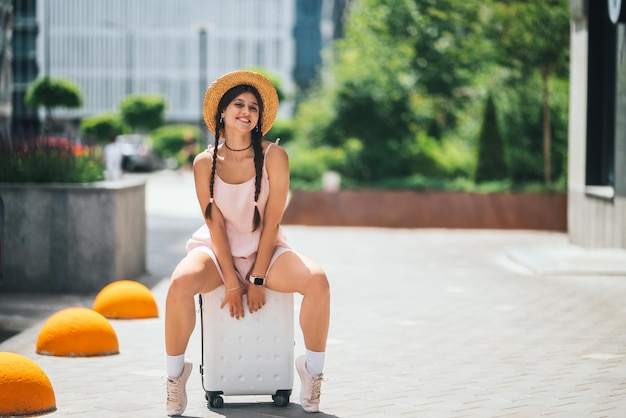 Молодая красивая кавказская женщина сидит на чемодане