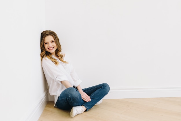 Young beautiful caucasian woman sitting on floor isolated with space for text