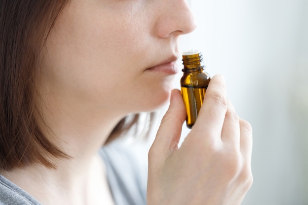 Young and beautiful Caucasian woman sniffing a tube of aromatic oil to check for Covid symptoms