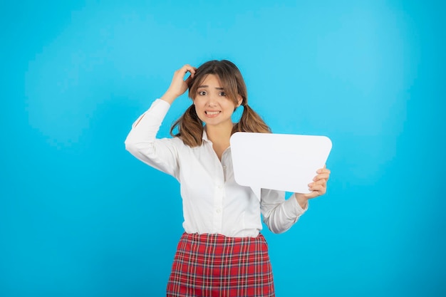 Giovane bella ragazza del college che tiene il bordo bianco dell'idea e le prude la testa. foto di alta qualità