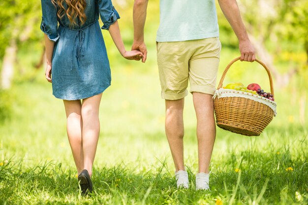 Young beautiful couple are going to picnic in summer park.