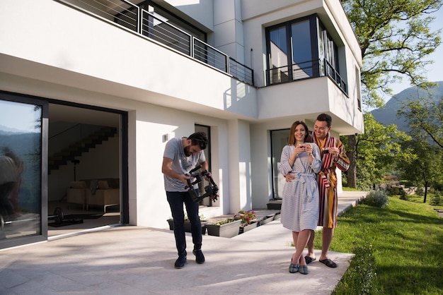 young beautiful couple in bathrobes are enjoying morning coffee in front of their luxury home villa