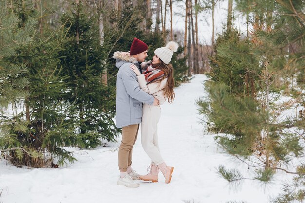 Young beautiful couple embraces in a winter coniferous forest