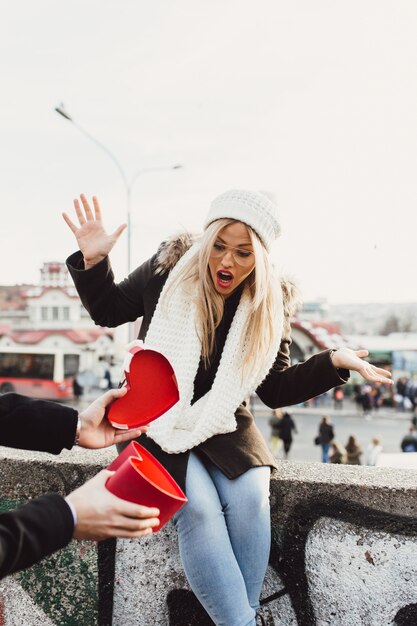 Young beautiful couple enjoying city walk at Valentine's day. Boyfriend gives his girlfriend a gift.