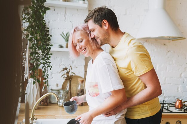 Foto giovani coppia bella famiglia felice divertirsi e lavare i piatti in cucina luminosa a casa