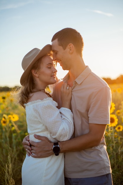 Young beautiful couple in love in a sunflower field at sunset Summer